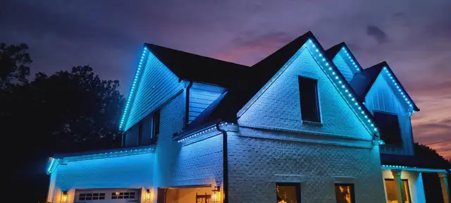 Blue house at night, roofline and peaks lit with permanent lighting