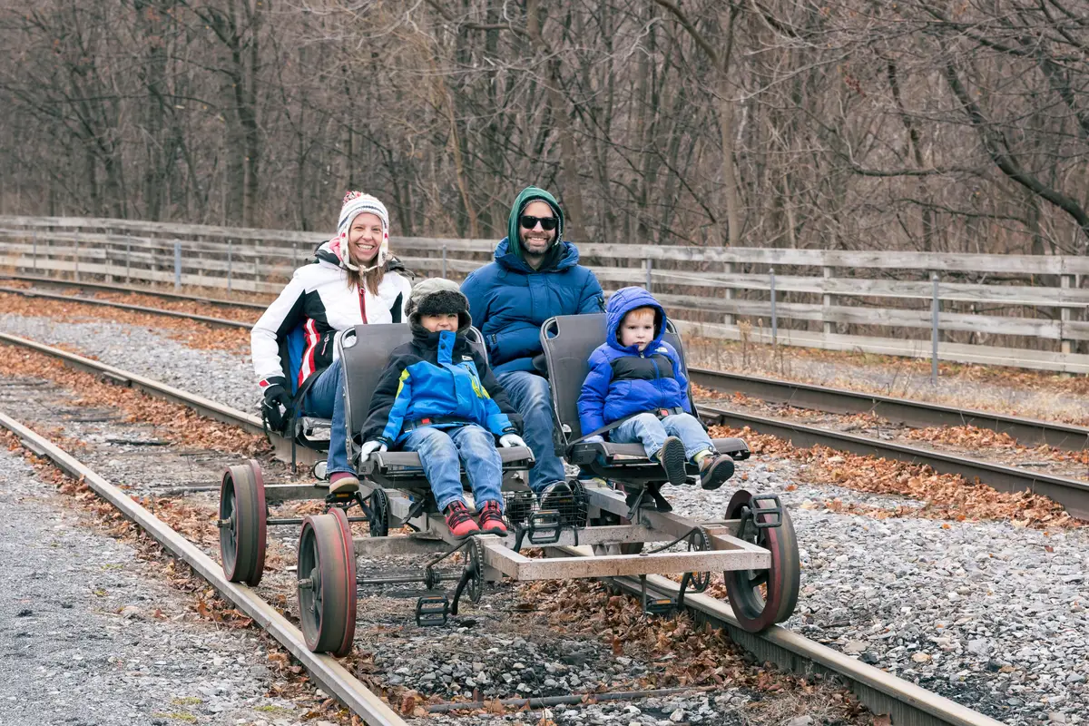 Family riding a railbike through a winter light display